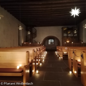 Kirche in Weißenbach mit Kerzen beleuchtet.